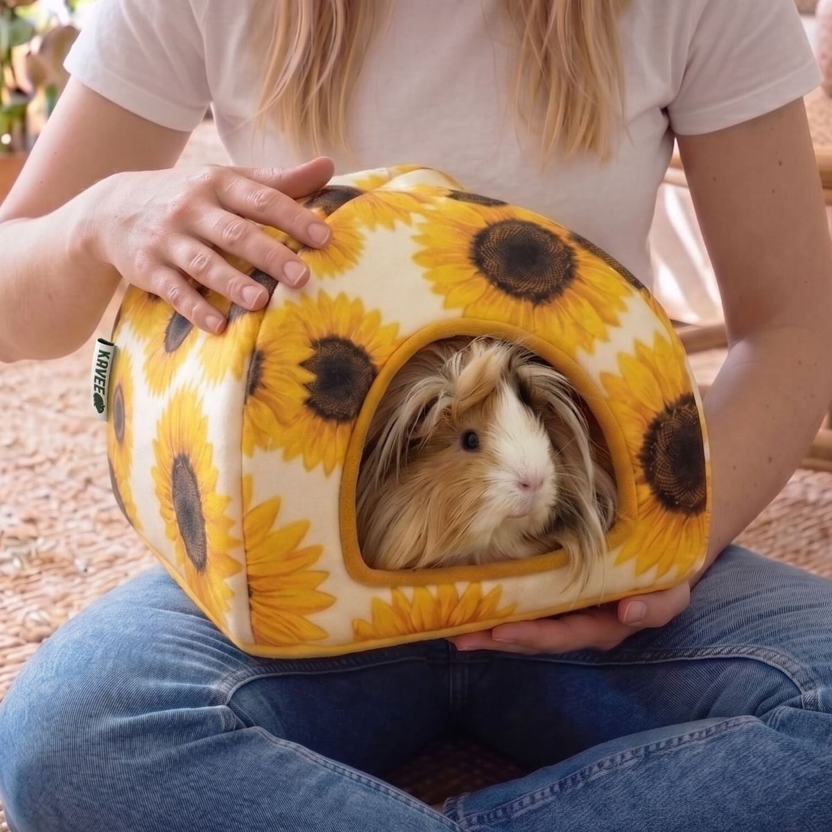 Vrouw houdt het schuilhuisje op schoot met een cavia in de opening