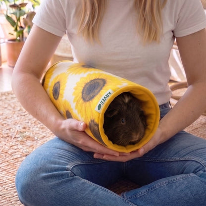 Vrouw in spijkerbroek houdt de tunnel op schoot met een bruine cavia erin