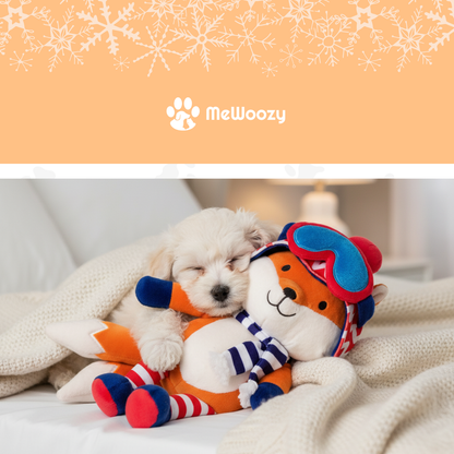 Witte puppy slaapt tegen de oranje pluche vos op een bed met deken