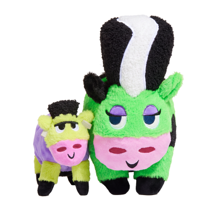 Groene pluche koeknuffel met zwart-witte kuif naast kleine paarse koeknuffel
