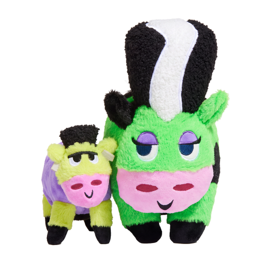 Groene pluche koeknuffel met zwart-witte kuif naast kleine paarse koeknuffel