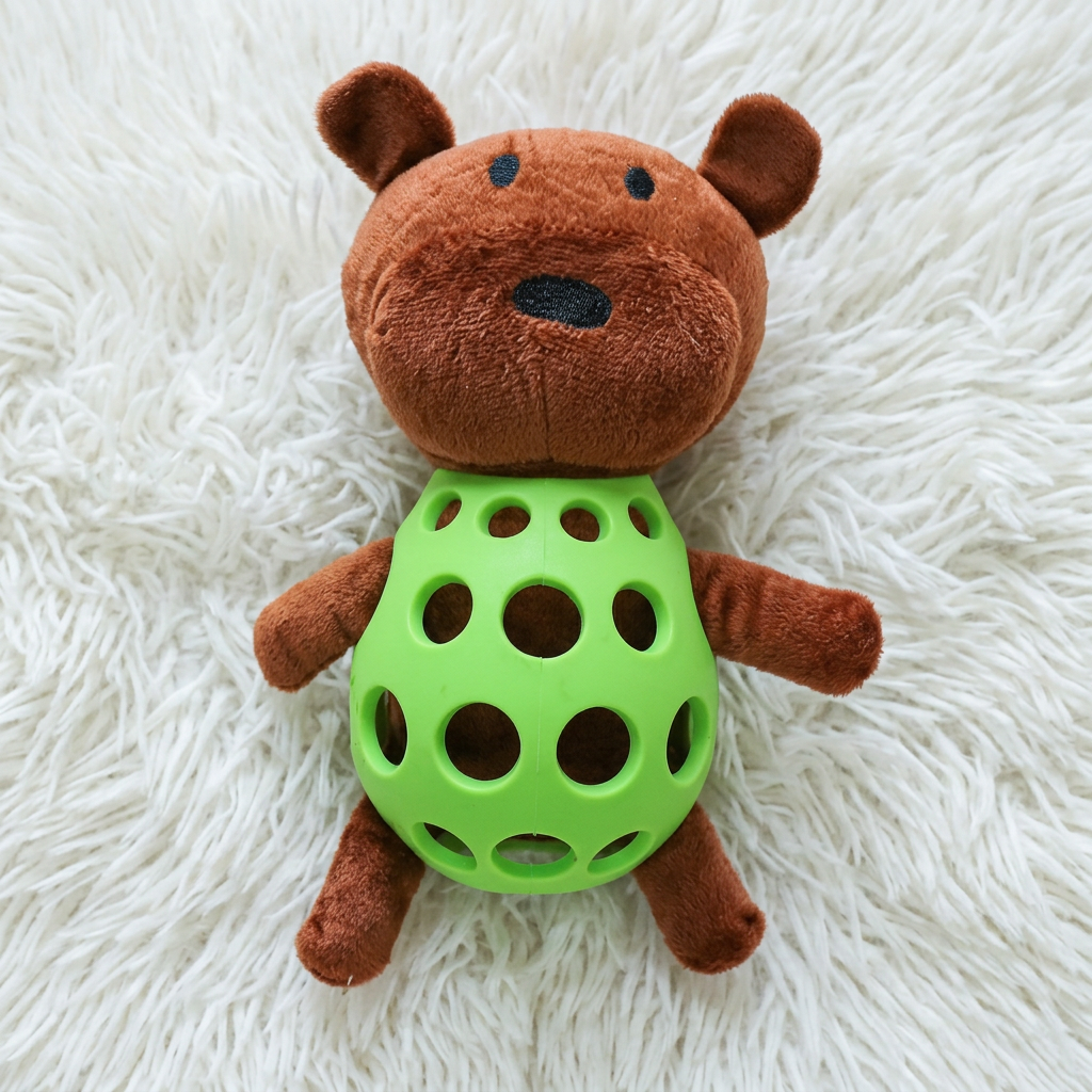 Bruine knuffelbeer met groene rubberen kauwbal als buik op wit kleed