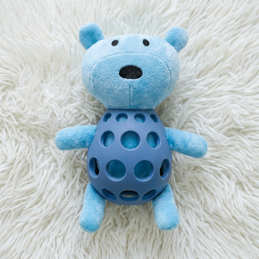 Blauwe knuffelbeer met donkerblauwe kauwbal van rubber op wit hoogpolig kleed