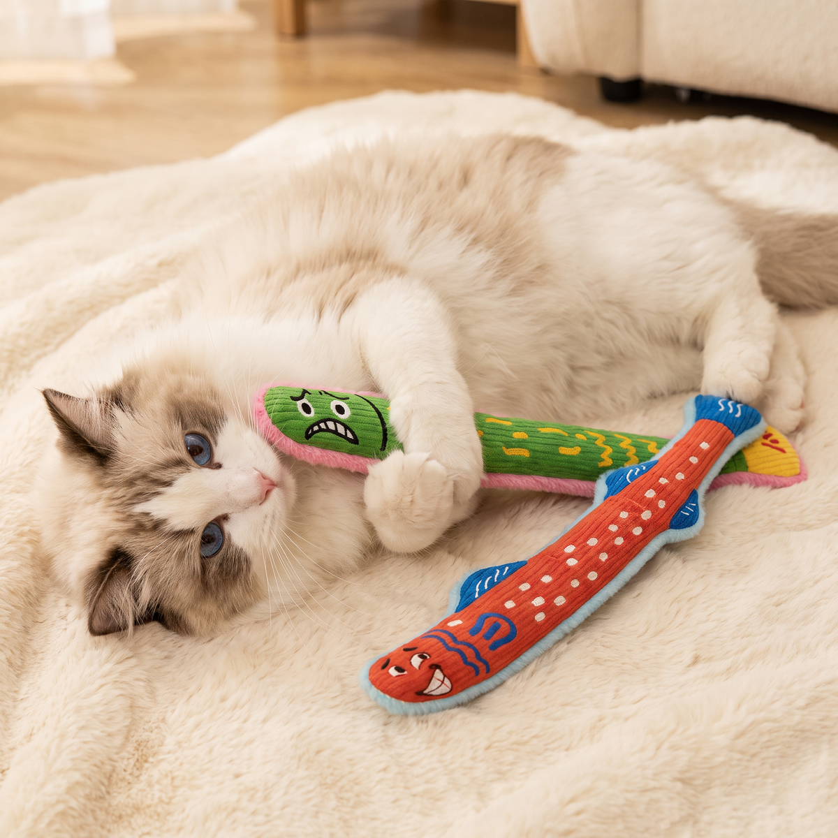 Ragdollkat ligt op een pluizig kleed met groene en oranje kattenkicker met catnip
