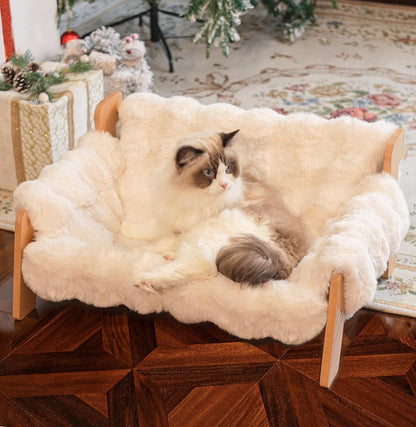Verhoogde hondenmand met houten frame en wit pluche, met ragdollkat erin