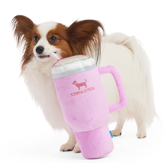 Roze pluche hondenknuffel in de vorm van een drinkbeker naast een papillon