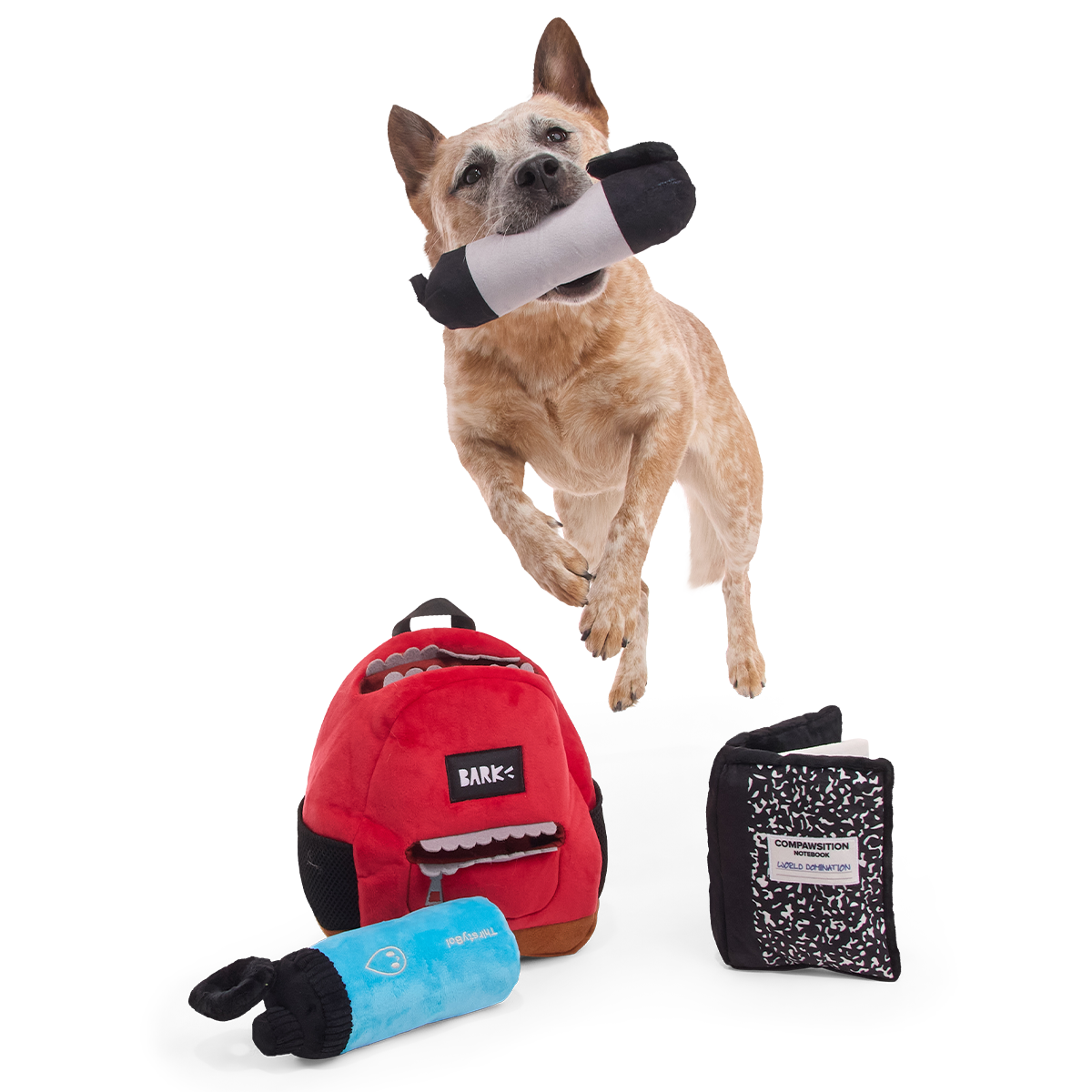 Springende hond met de pluche stift in de bek naast de rugzak