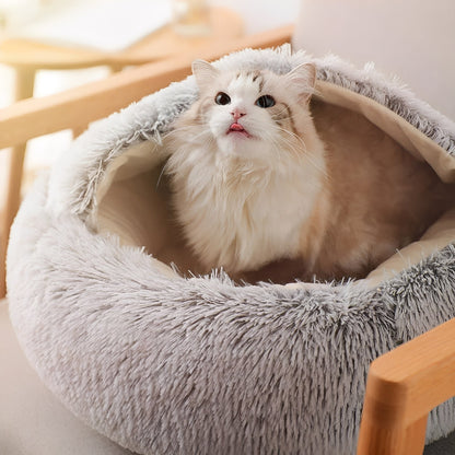 Witte kat met grijze vlekken zit rechtop in grijze kattenmand op een stoel