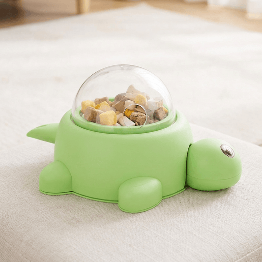 Groene snackdispenser in schildpadvorm met doorzichtige koepel vol snacks op een vloerkleed