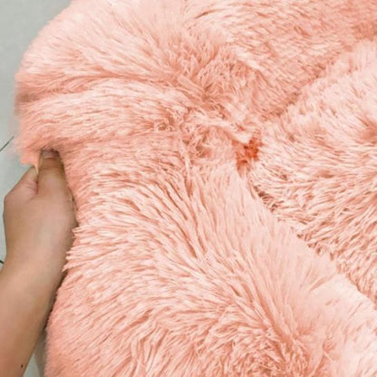Hand knijpt in de lange roze pluche stof van de kattenmand